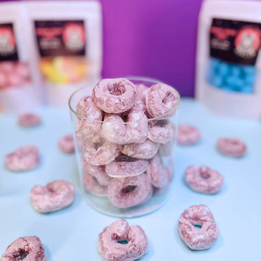 Gefriergetrocknete Passionsfruchtringe (Halal) in einem Glasbehälter mit violetter Färbung – Produktdarstellung von Astrocat Candy.