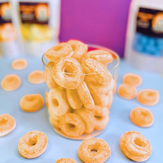 Gefriergetrocknete Pfirsichringe (Halal) in einem transparenten Glasbehälter – Vorderansicht des Produkts von Astrocat Candy vor neutralem Hintergrund.