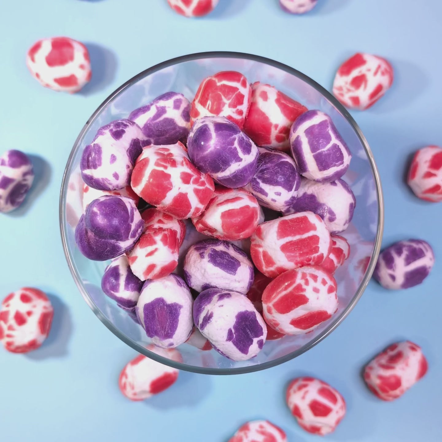 Gefriergetrocknete Krachmacher Berries fallen von oben in einen Glasbehälter – Draufsicht auf die bunte Beerenmischung von Astrocat Candy.