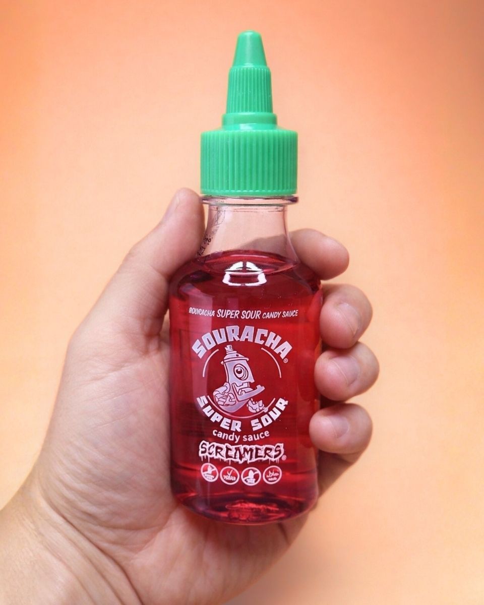 Souracha Super Sour Candy Sauce wird in der Hand gehalten und als Produkt präsentiert.